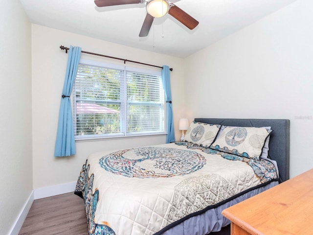 bedroom featuring ceiling fan, baseboards, and wood finished floors