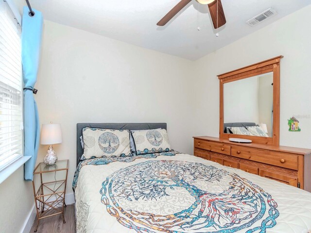 bedroom featuring baseboards, ceiling fan, visible vents, and wood finished floors