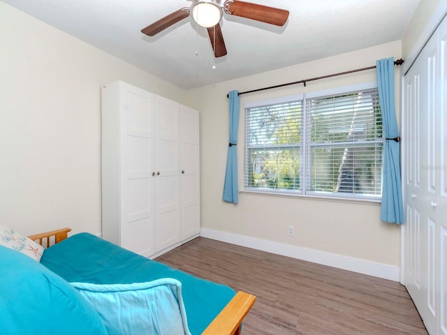 bedroom with a closet, wood finished floors, a ceiling fan, and baseboards