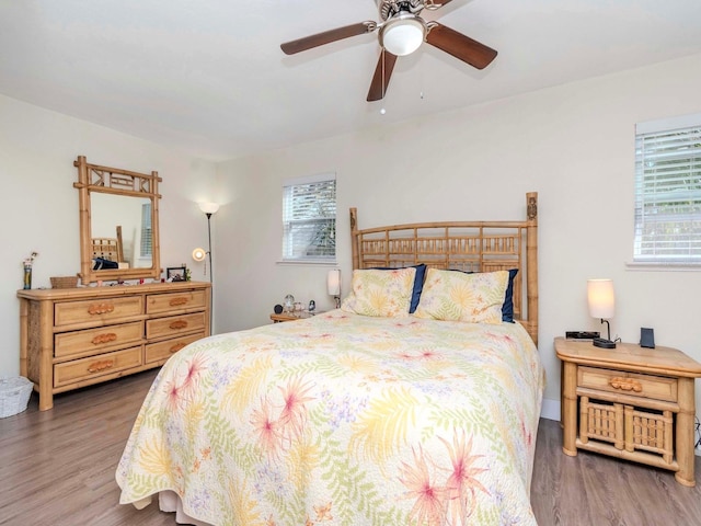 bedroom featuring ceiling fan, multiple windows, and wood finished floors