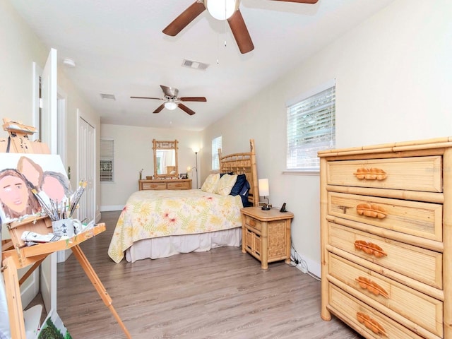 bedroom with a ceiling fan, baseboards, visible vents, and light wood finished floors