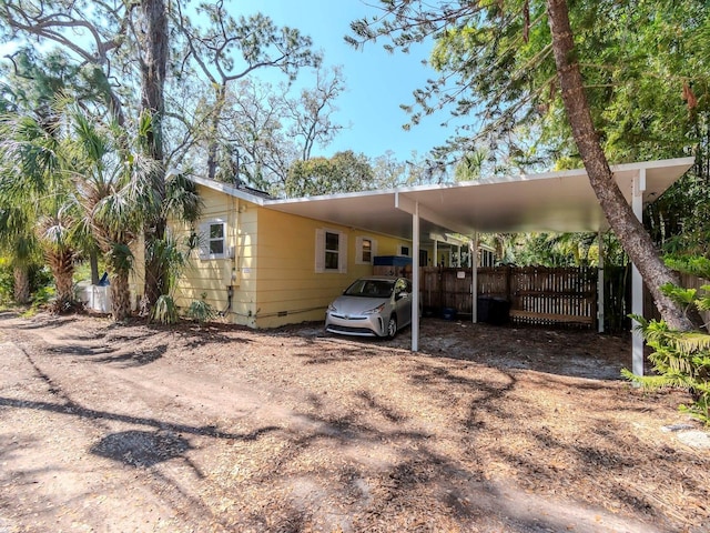 exterior space featuring driveway, fence, and a carport