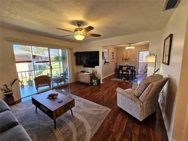 living room featuring baseboards, visible vents, a ceiling fan, wood finished floors, and a textured ceiling