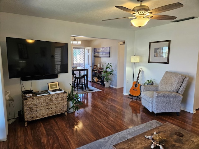 living area featuring visible vents, a ceiling fan, a textured ceiling, wood finished floors, and baseboards