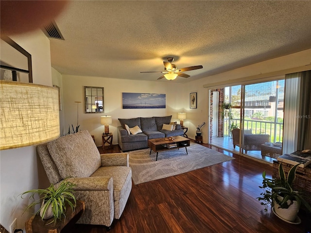 living area with ceiling fan, a textured ceiling, visible vents, and wood finished floors