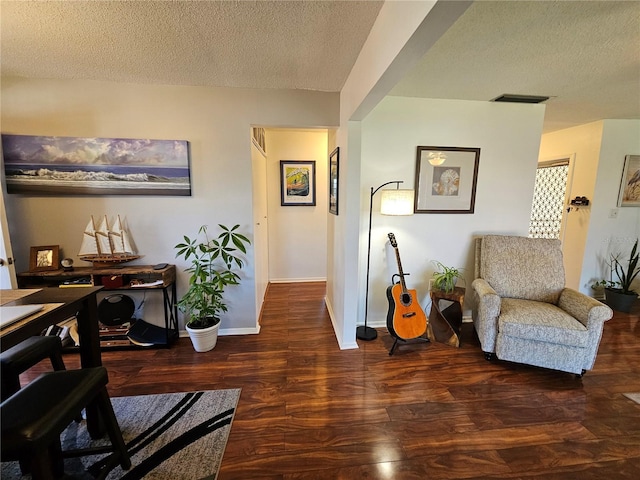 sitting room with a textured ceiling, wood finished floors, visible vents, and baseboards