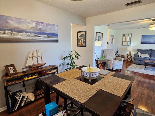 dining room with a textured ceiling, ceiling fan, hardwood / wood-style flooring, and visible vents