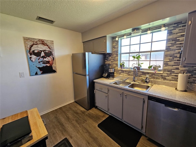 kitchen with tasteful backsplash, visible vents, dark wood-style flooring, stainless steel appliances, and a sink