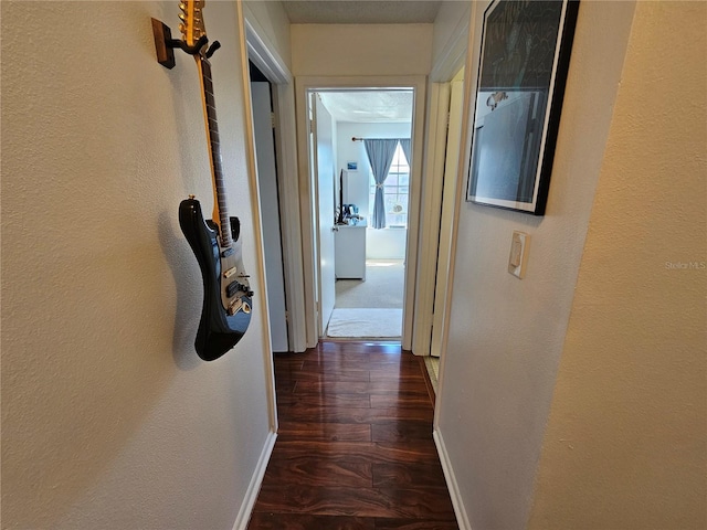 hallway featuring baseboards and wood finished floors