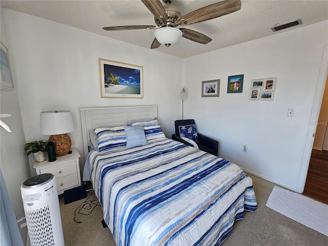 carpeted bedroom with visible vents, ceiling fan, a textured ceiling, and baseboards