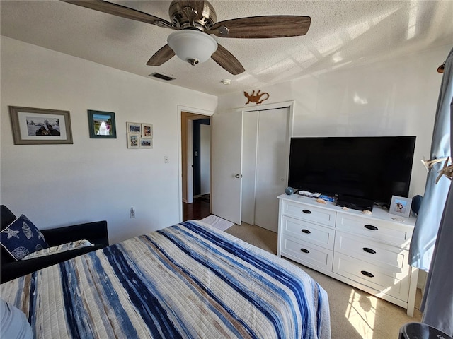 bedroom with light carpet, a closet, visible vents, and a textured ceiling