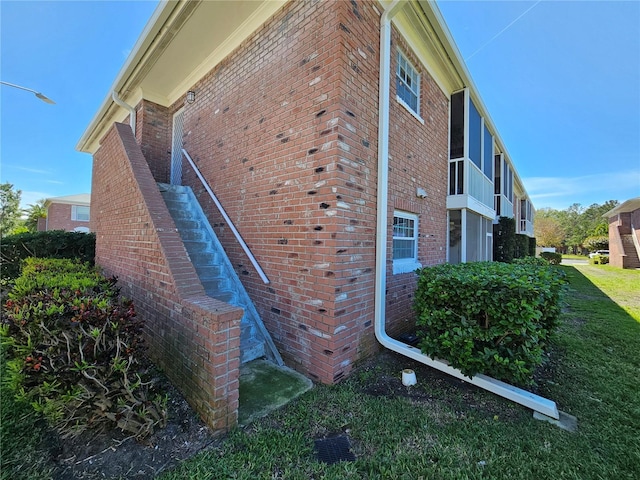 view of home's exterior with brick siding and a lawn