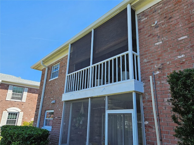 view of property exterior featuring a sunroom and brick siding