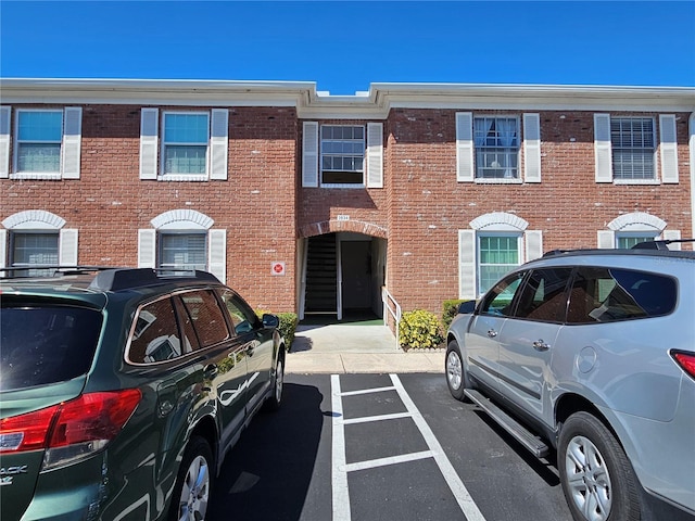 view of property with uncovered parking and brick siding