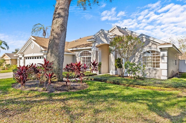 view of front of house with an attached garage, a front lawn, and stucco siding