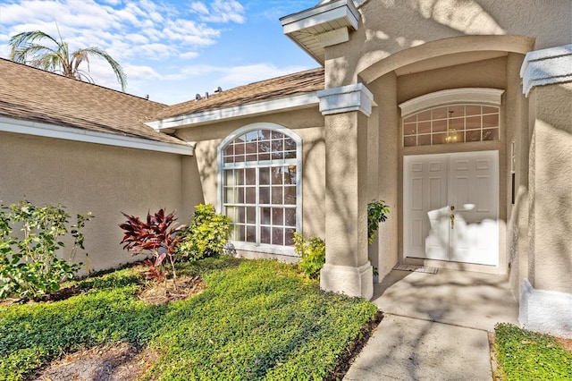 property entrance featuring a shingled roof and stucco siding