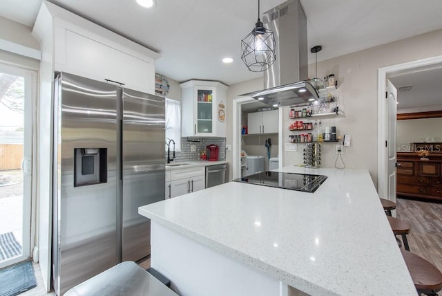 kitchen with a breakfast bar area, tasteful backsplash, appliances with stainless steel finishes, a sink, and island range hood