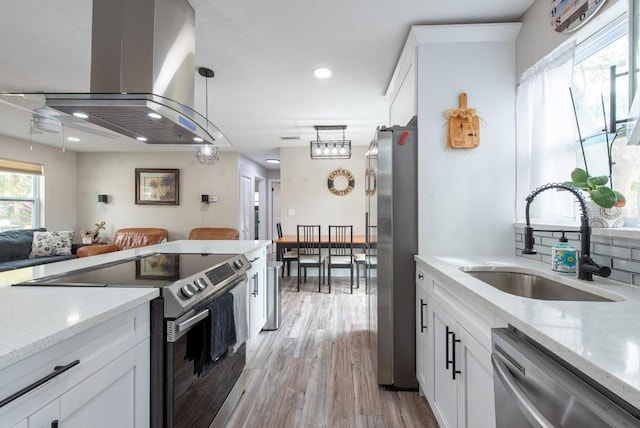 kitchen with white cabinetry, appliances with stainless steel finishes, island range hood, and a sink