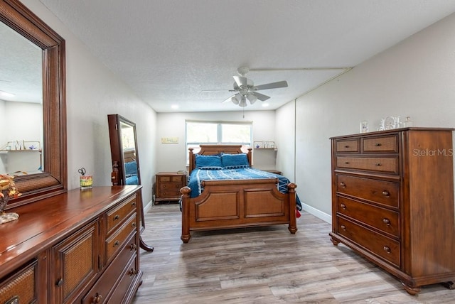 bedroom with light wood finished floors, baseboards, and a textured ceiling