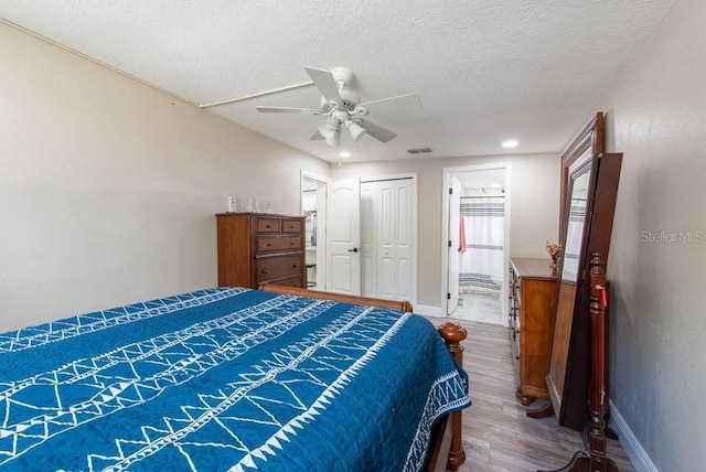 bedroom featuring visible vents, a textured ceiling, baseboards, and wood finished floors