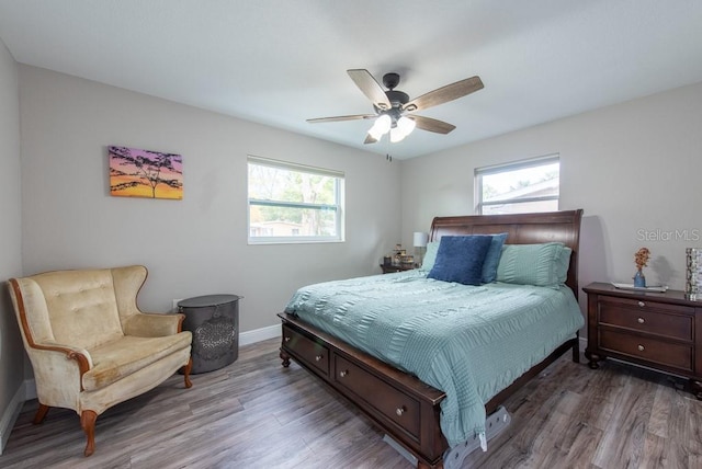 bedroom with ceiling fan, multiple windows, wood finished floors, and baseboards