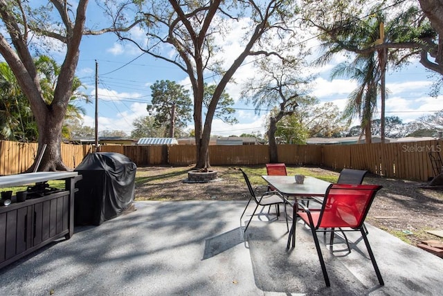 view of patio / terrace featuring an outdoor fire pit, a grill, a fenced backyard, and outdoor dining space