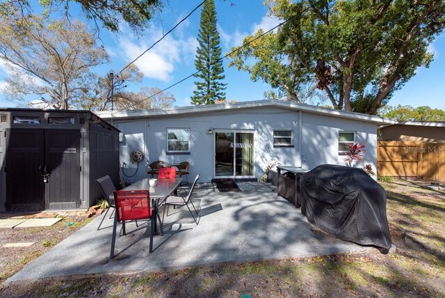 back of house featuring an outbuilding, a shed, a patio area, and fence