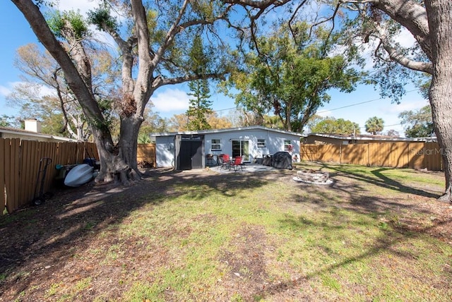 view of yard with a fenced backyard, a fire pit, and a patio