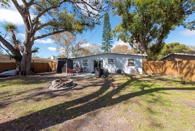 back of house featuring an outdoor fire pit, a fenced backyard, a yard, and a patio