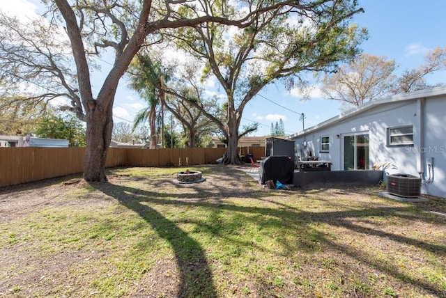 view of yard featuring cooling unit, a fenced backyard, and a fire pit