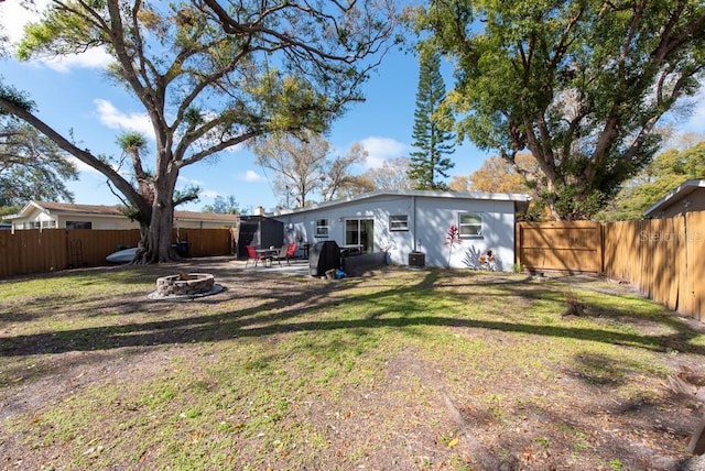 back of house featuring cooling unit, a fenced backyard, a fire pit, and a lawn