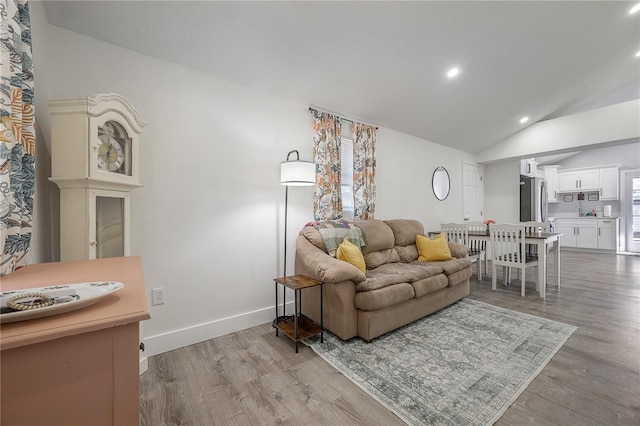 living room with vaulted ceiling, recessed lighting, baseboards, and light wood-style floors