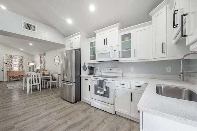 kitchen with visible vents, white cabinets, vaulted ceiling, a sink, and white appliances