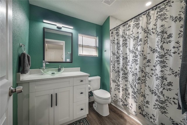 bathroom featuring visible vents, a shower with shower curtain, toilet, vanity, and wood finished floors