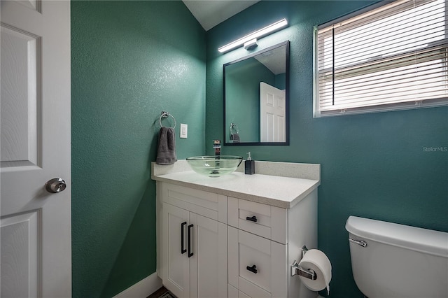 bathroom featuring a textured wall, vanity, and toilet