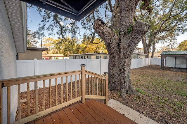 wooden deck featuring a fenced backyard, a storage unit, and an outbuilding