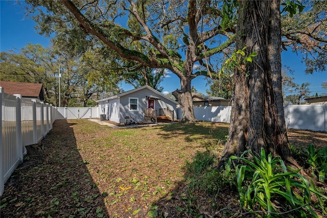 view of yard with a fenced backyard and a gate