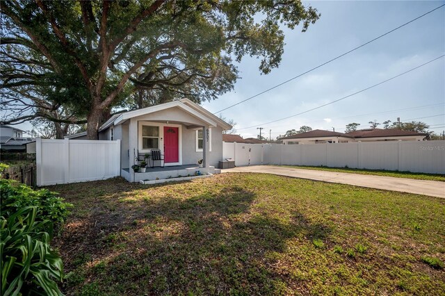 view of front of property featuring stucco siding, fence, concrete driveway, and a front yard