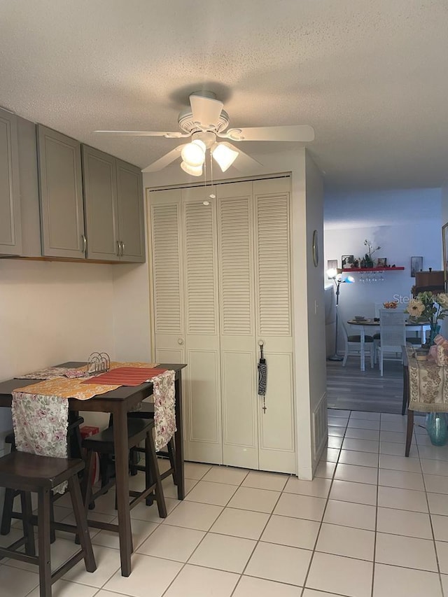 dining space with ceiling fan, a textured ceiling, and light tile patterned flooring