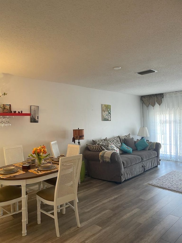 living room featuring a textured ceiling, visible vents, and wood finished floors