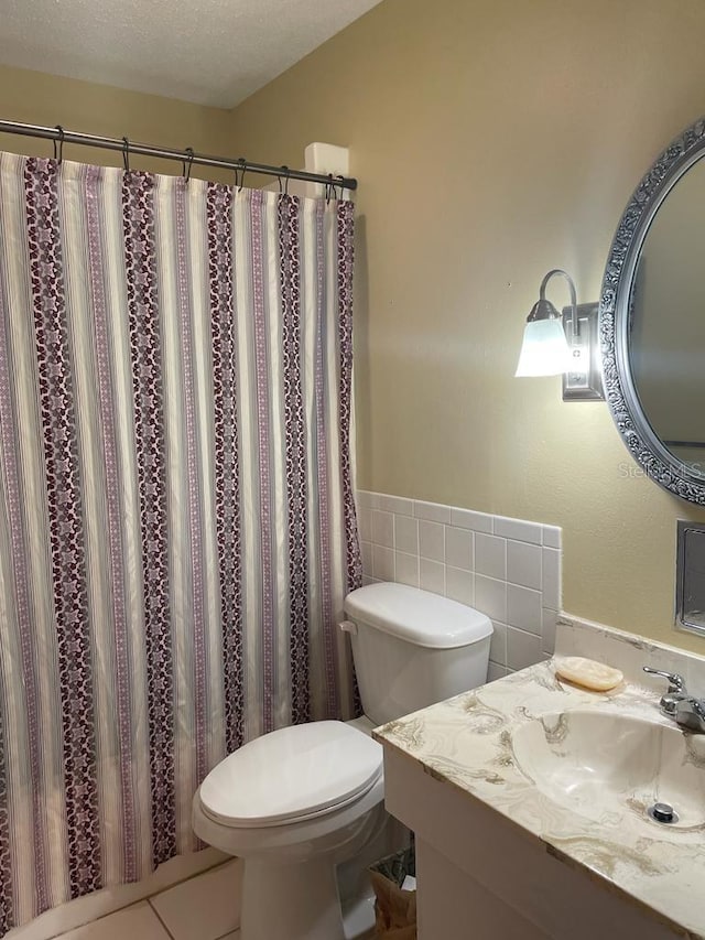 full bath featuring a textured ceiling, curtained shower, vanity, and toilet