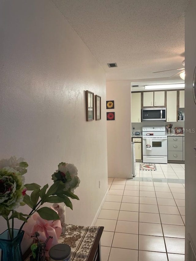 corridor featuring light tile patterned flooring, visible vents, and a textured ceiling