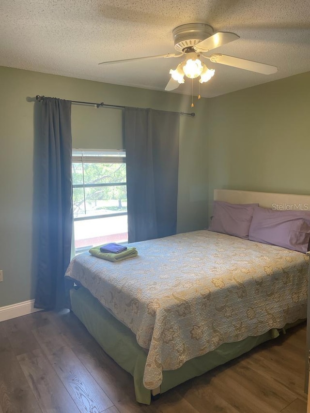 bedroom with ceiling fan, a textured ceiling, and wood finished floors