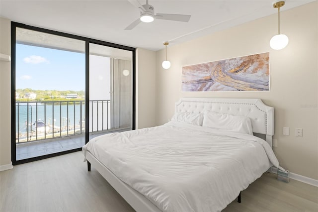 bedroom featuring access to exterior, baseboards, wood finished floors, and floor to ceiling windows