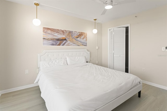 bedroom featuring a closet, ceiling fan, light wood-style flooring, and baseboards