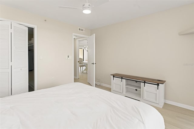 bedroom featuring a closet, visible vents, light wood-style floors, ceiling fan, and baseboards