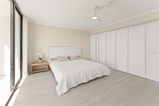 bedroom with light wood-style flooring, a closet, ceiling fan, and crown molding