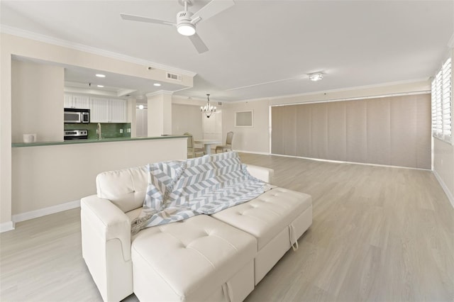 living room featuring ornamental molding, light wood-type flooring, visible vents, and baseboards