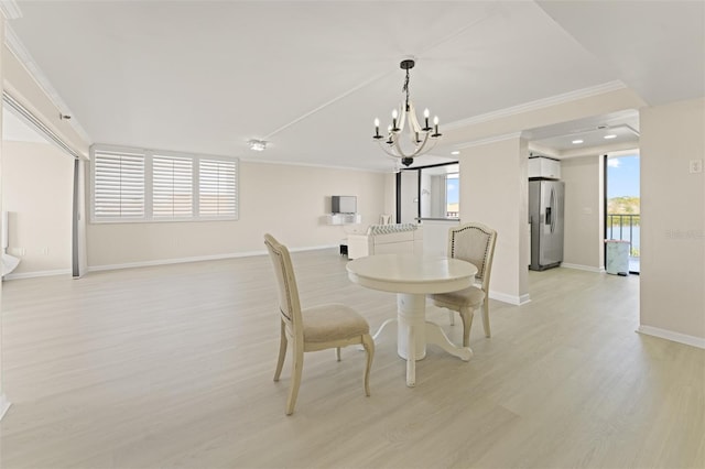 dining room with crown molding, light wood-style flooring, baseboards, and an inviting chandelier