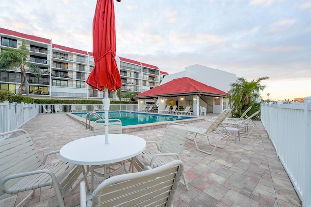 community pool with a patio, a gazebo, and fence